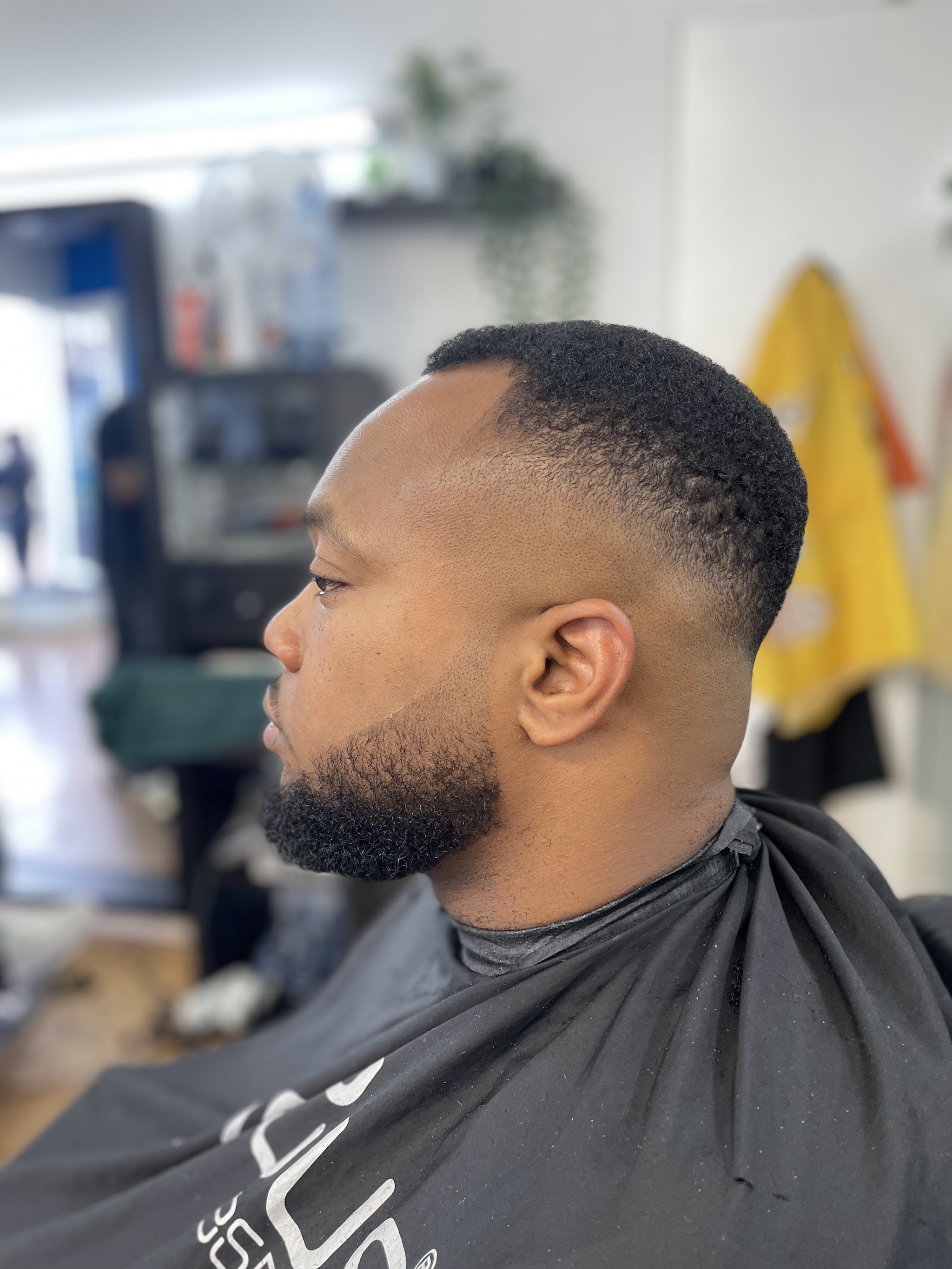 Strakke skin fade en volle baard, van opzij gezien in de zaak