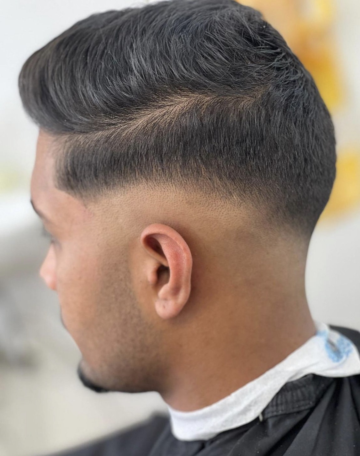 Low fade met een opgeföhnde quiff, van achteren en opzij